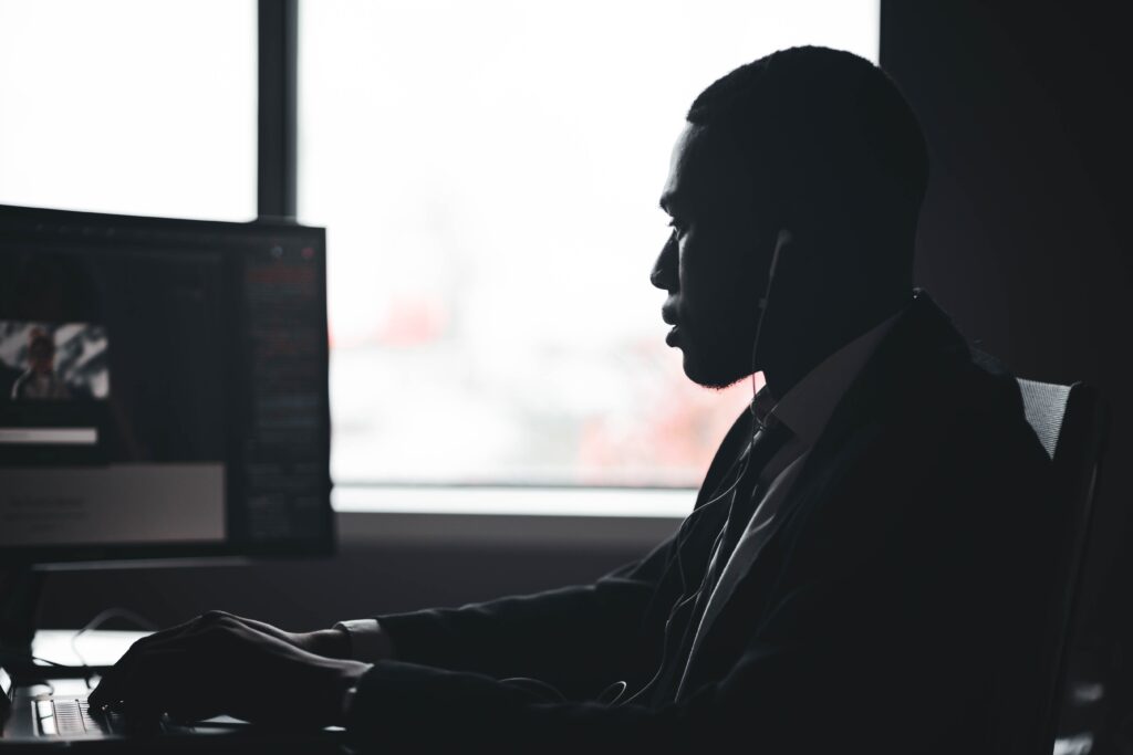 Silhouette of a man working at a computer desk in a modern office setting.